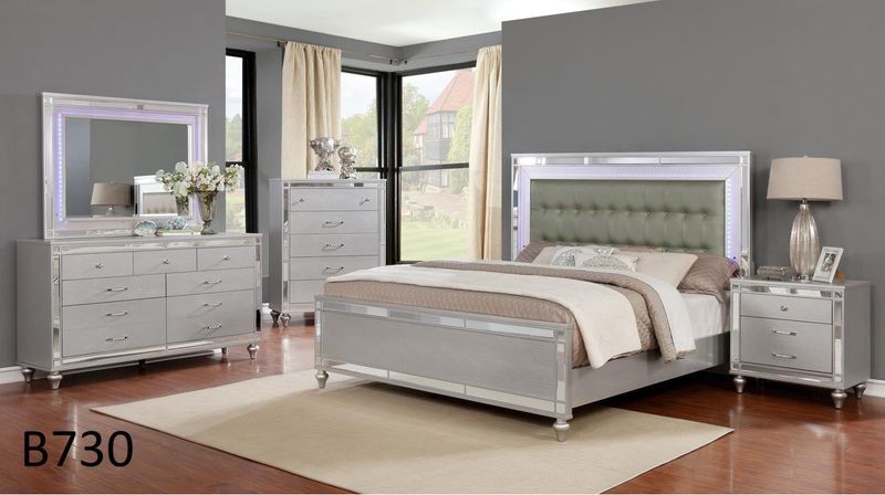 A bedroom with a bed , dresser , nightstand , mirror and rug.