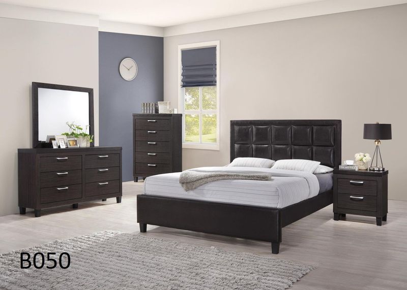 A bedroom with a bed , dresser , nightstand , mirror and rug.