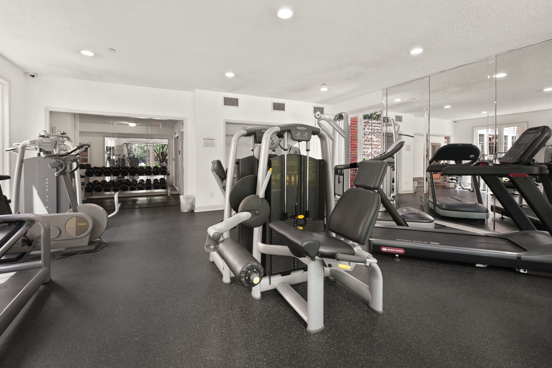 Modern gym interior with exercise machines, treadmills, mirrors, and bright white walls