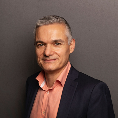 A man in a suit and pink shirt is smiling for the camera.