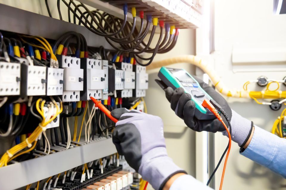 Electrician testing wires in electrical panel with a multimeter.