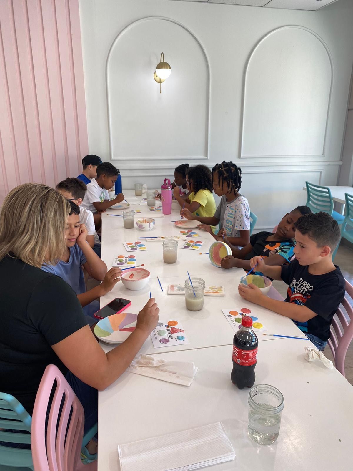 A group of children are sitting at a long table in a restaurant.