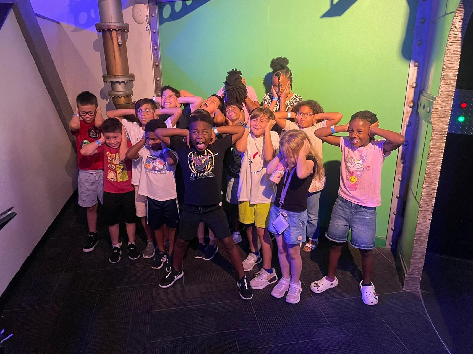 A group of children are posing for a picture in front of a green screen.