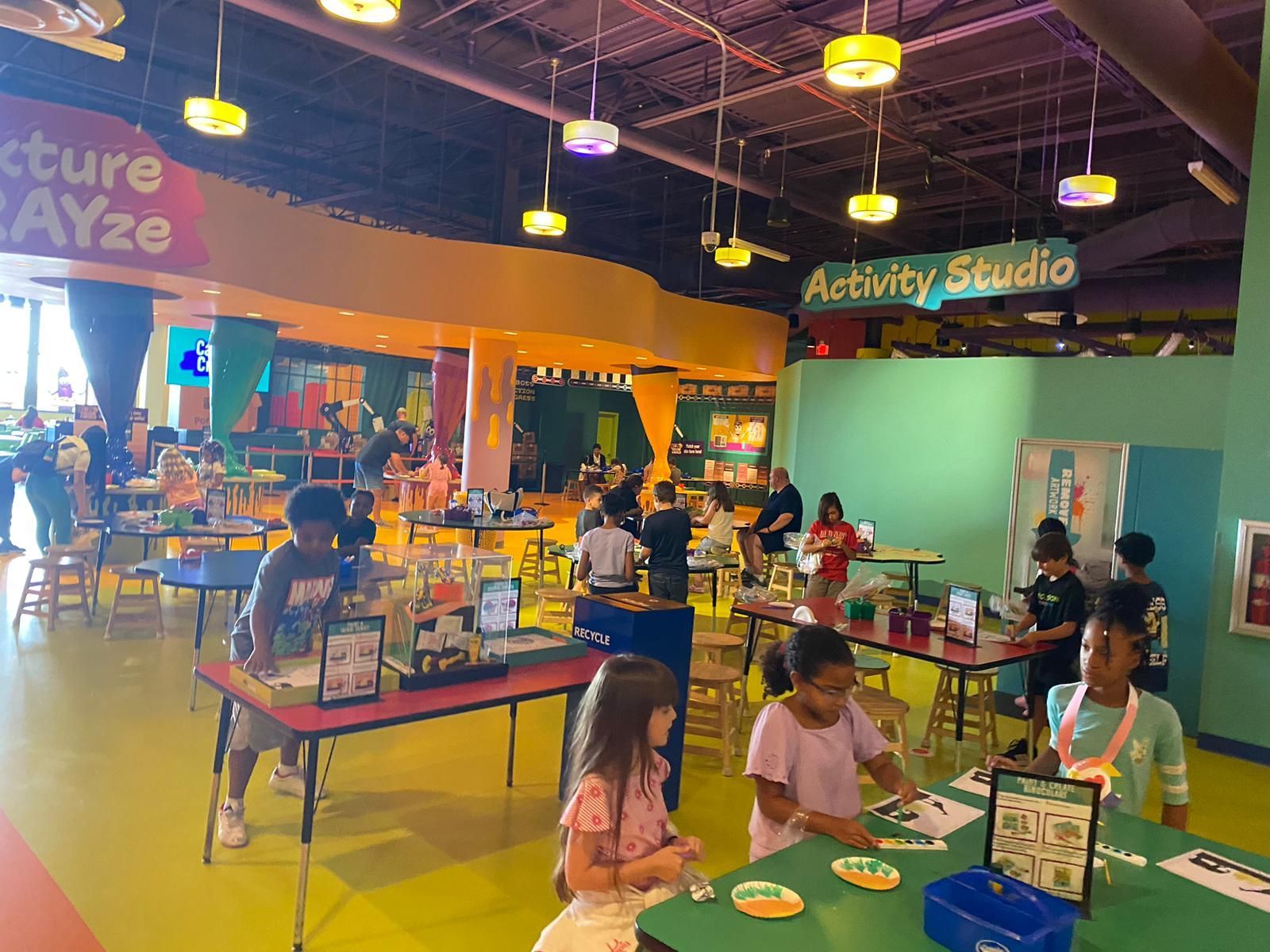Kids at art tables in a brightly colored Activity Studio.
