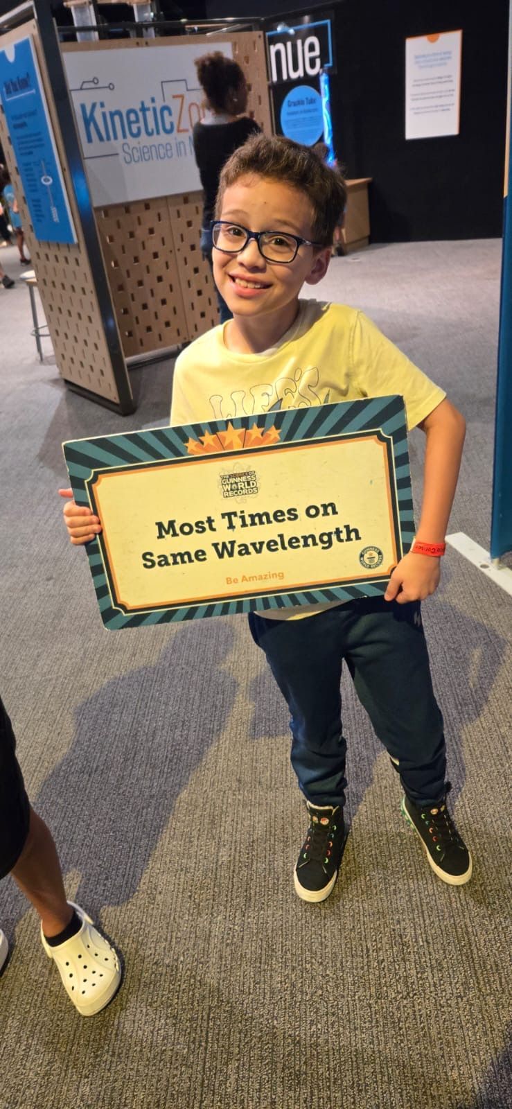 A young boy is holding a sign that says `` meet thomas on some wavelength ''.