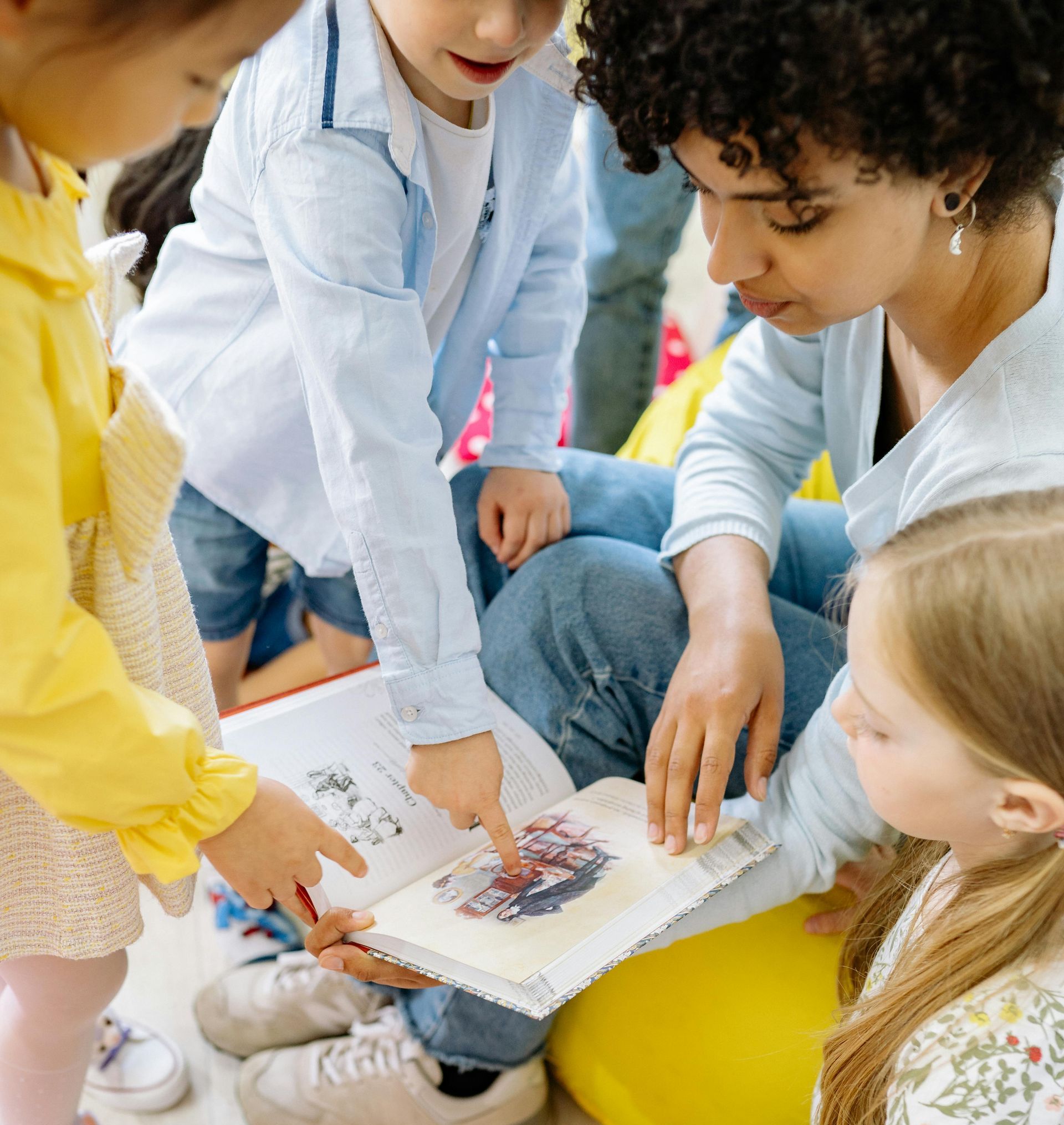 A woman is reading a book to a group of children