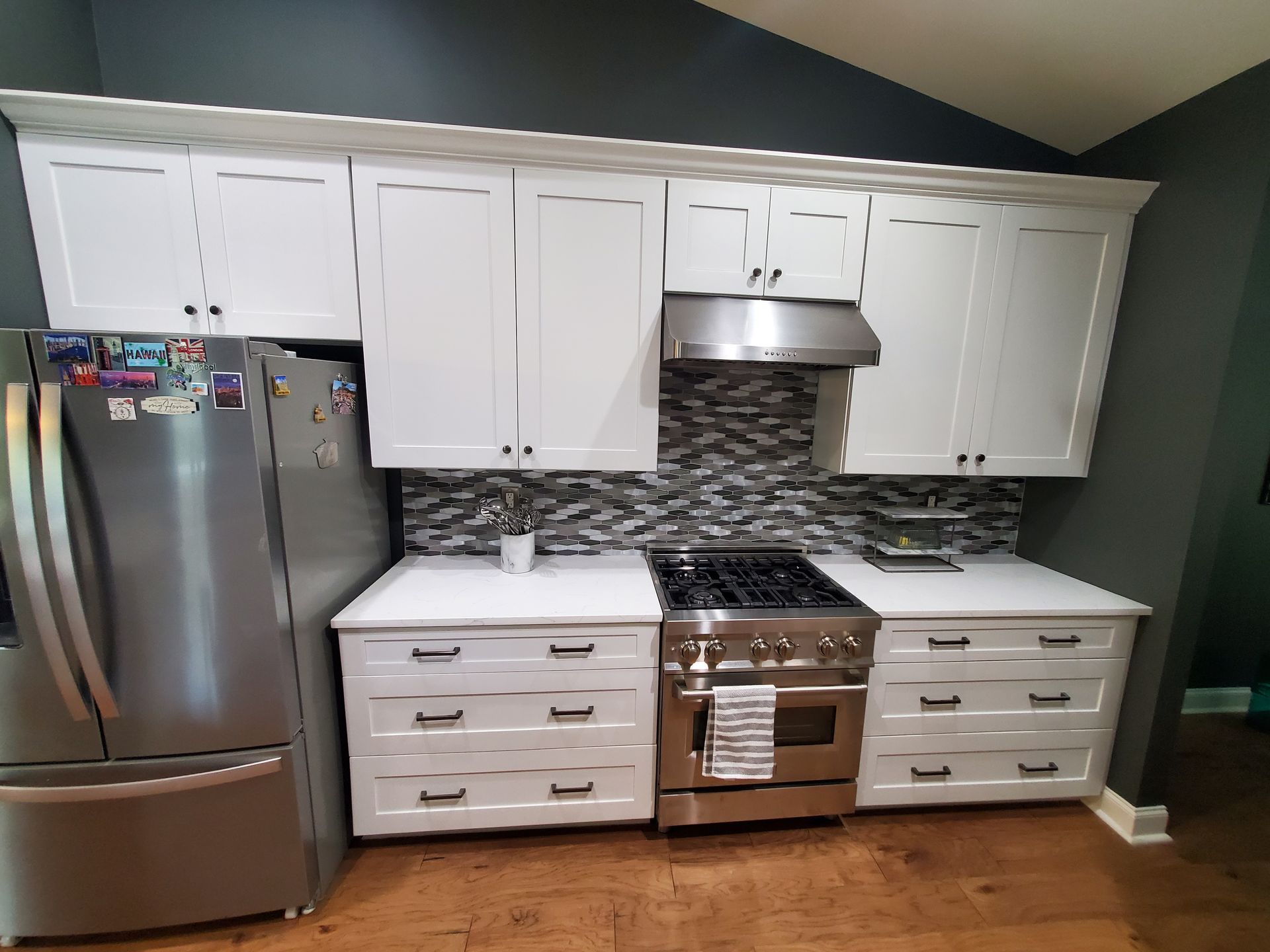 A kitchen with white cabinets , stainless steel appliances , and a refrigerator.