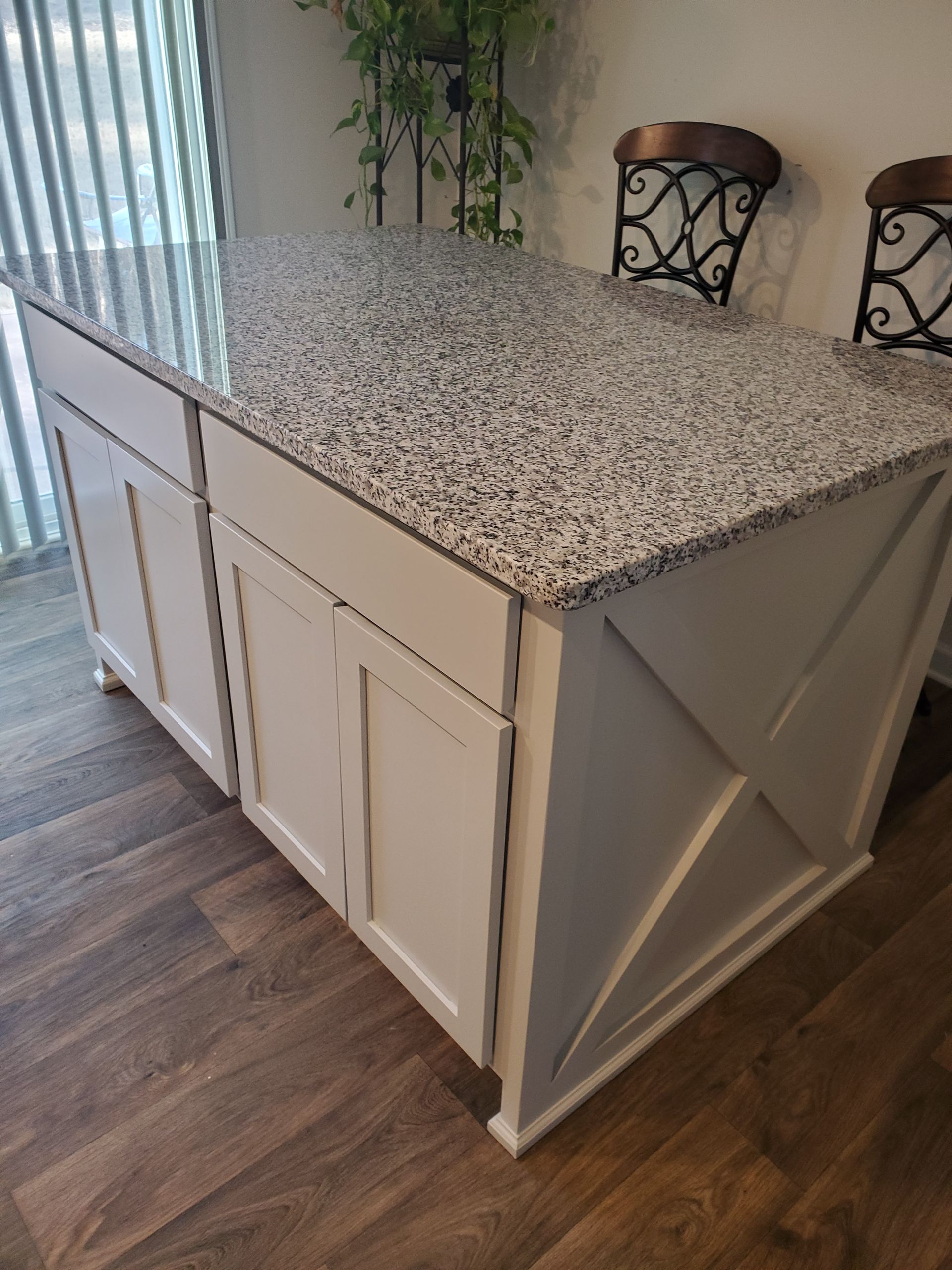 A kitchen island with granite counter tops and white cabinets.