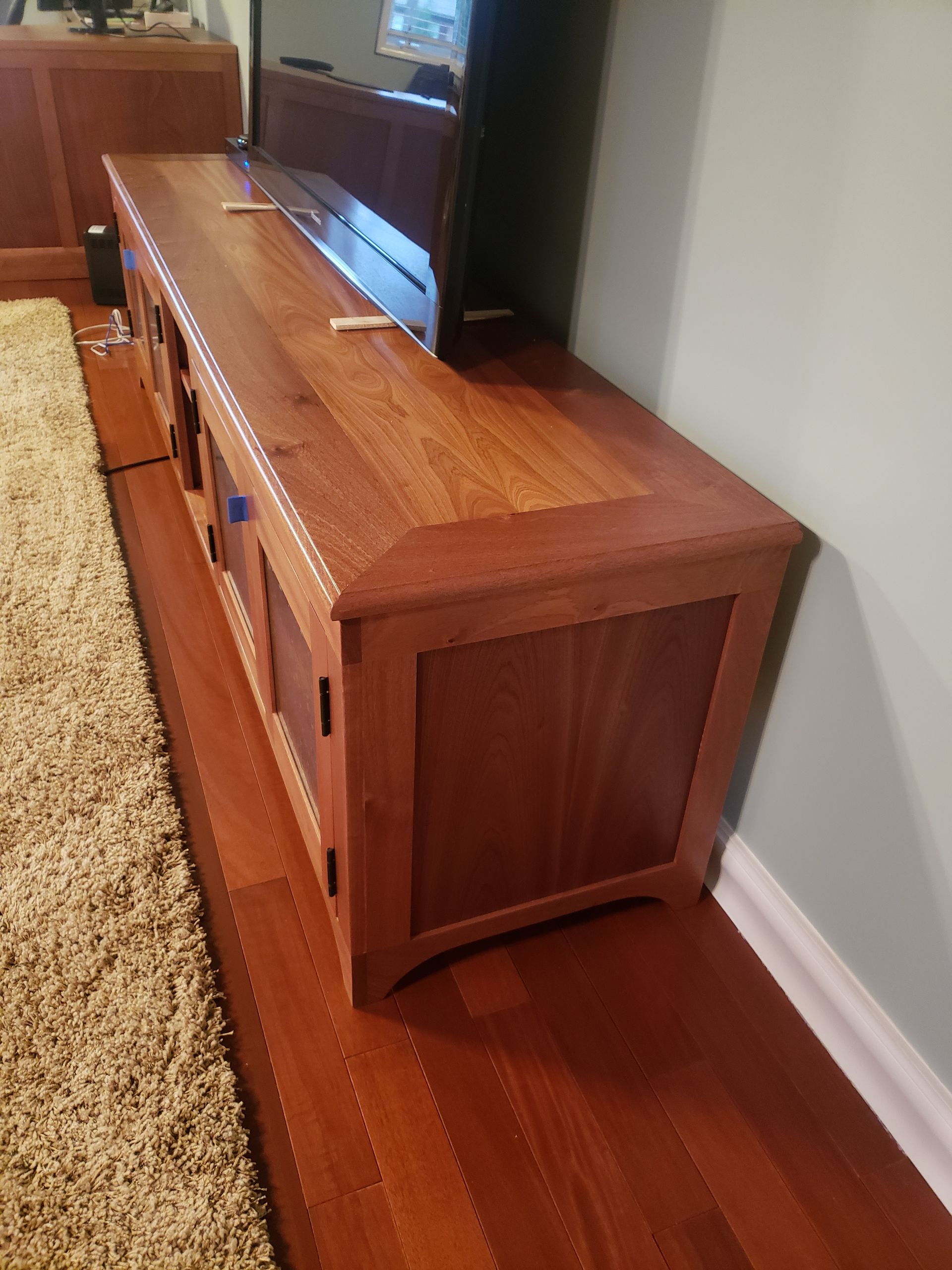 A wooden entertainment center in a living room next to a rug