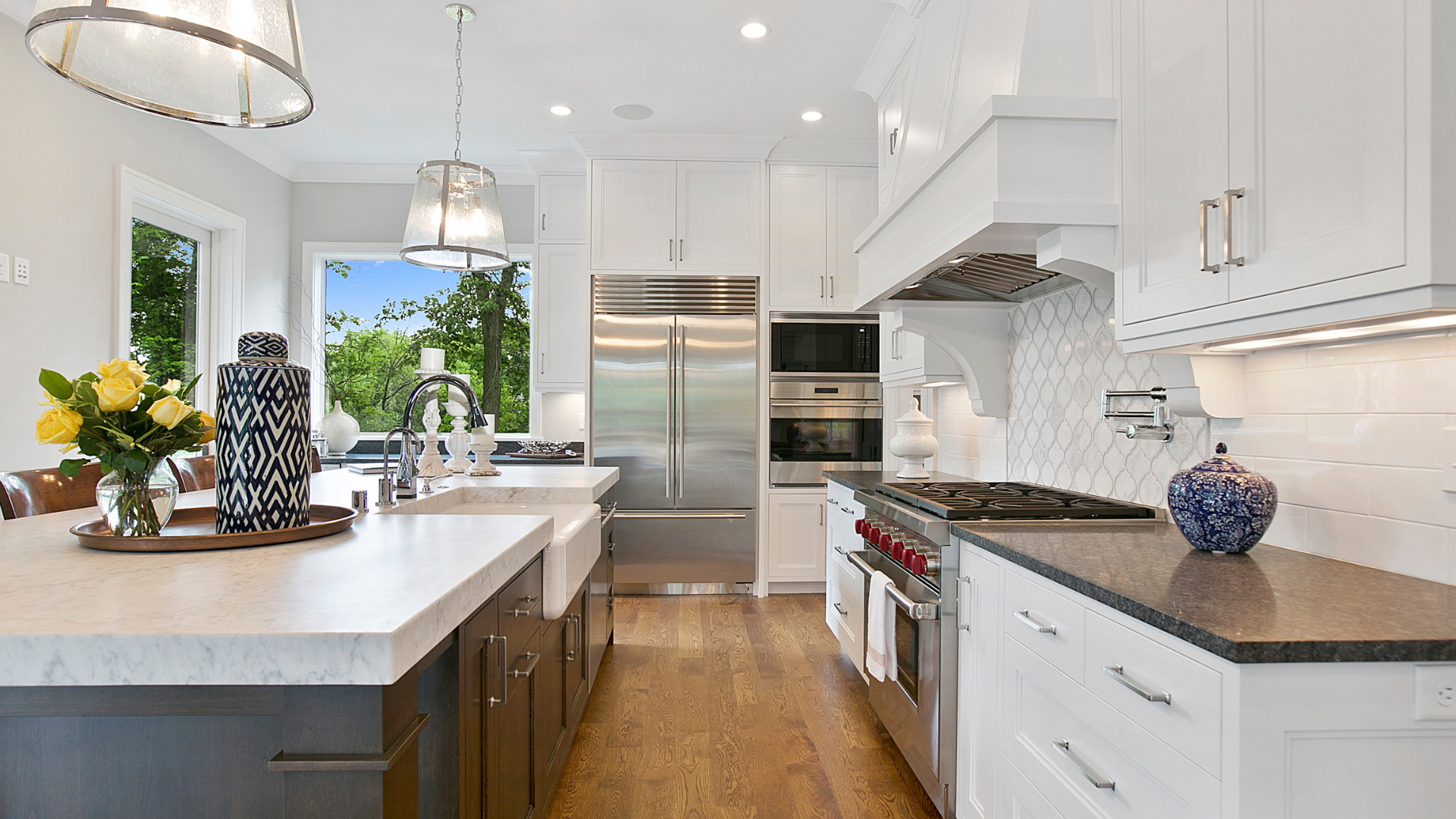 Modern kitchen with white cabinets, stainless steel appliances, and large island with sink.