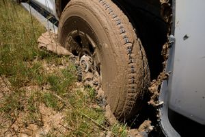 Close-up of a mud-covered tire on a vehicle stuck in grass and dirt