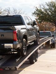 Silver pickup truck loaded on a flatbed tow truck on a sunny street