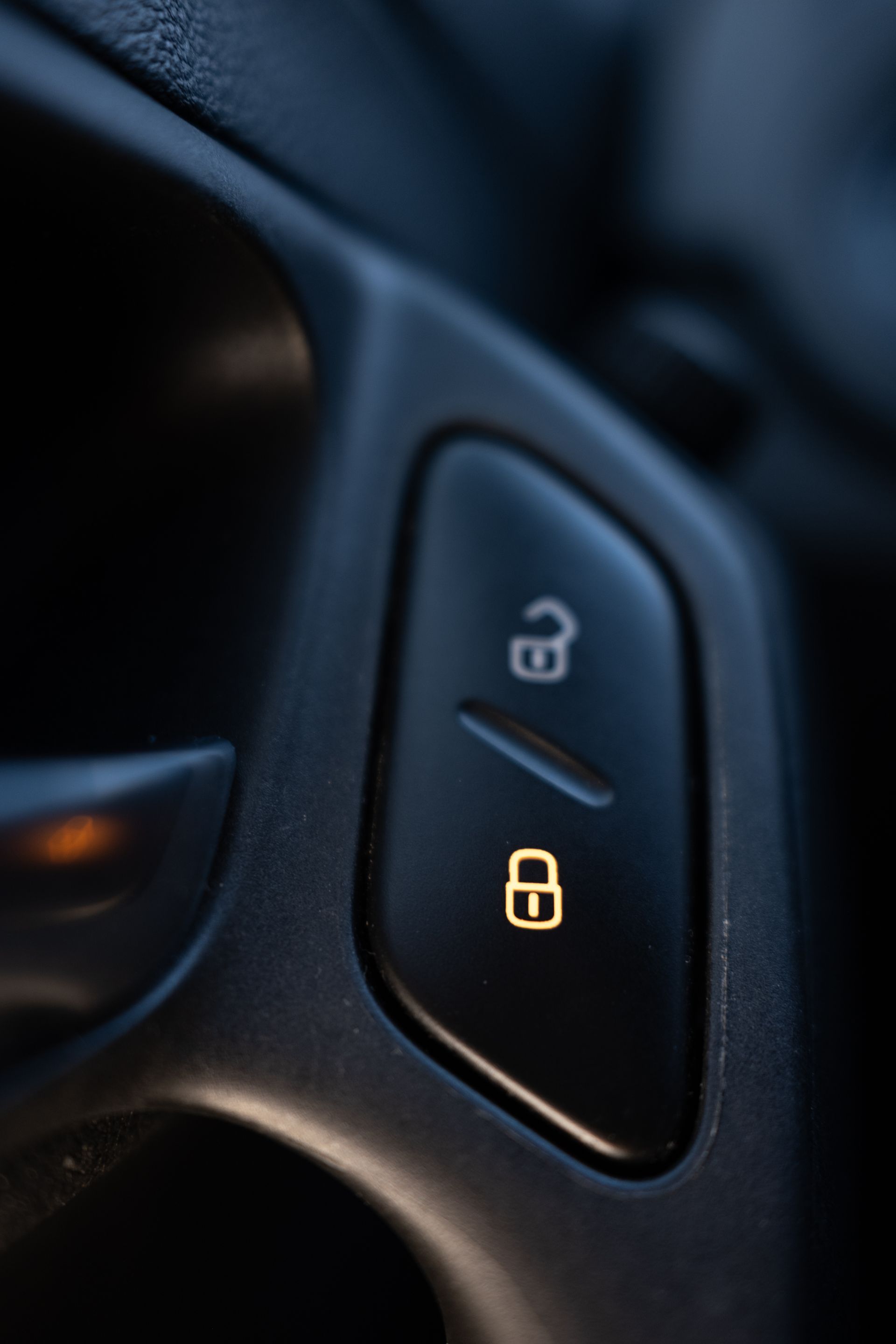 Close-up of a car door lock button with illuminated lock and unlock icons