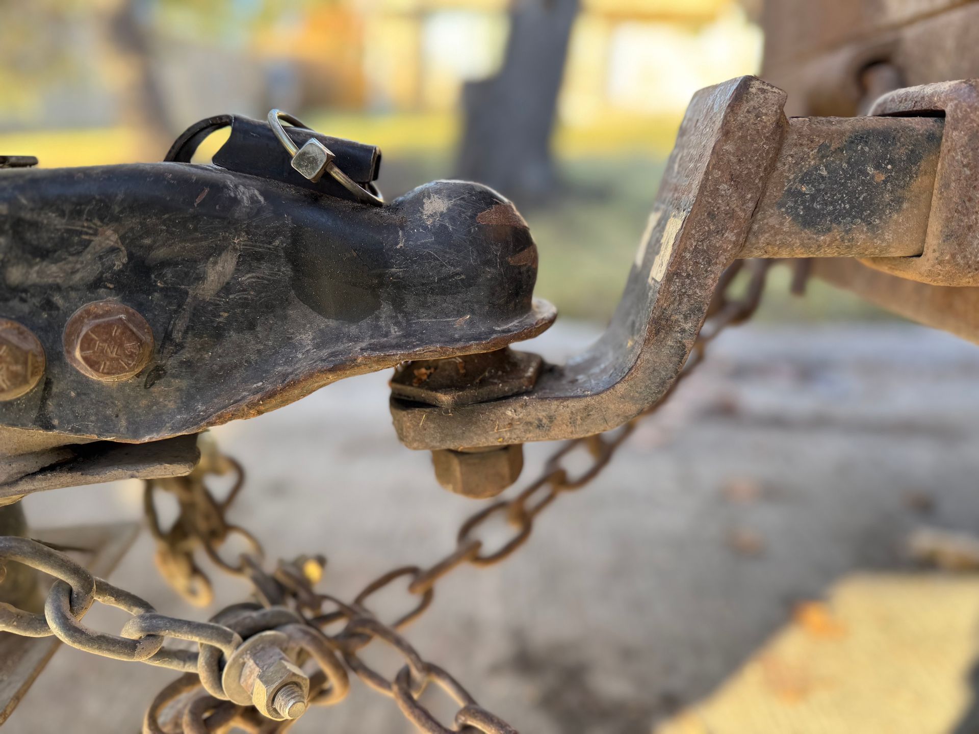 Close-up of a rusty trailer hitch secured with a chain lock and coupler pin.