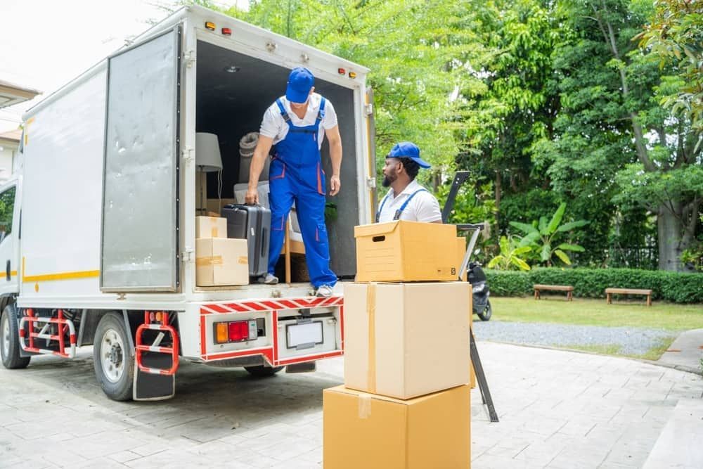 A Man Is Loading Boxes Into A Moving Truck — Byron Coast Removals In Pottsville, NSW