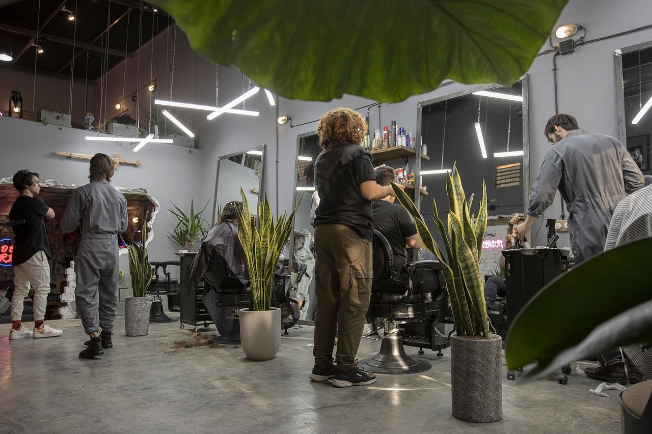 A senior stylist teaches haircut techniques to an apprentice in a salon.