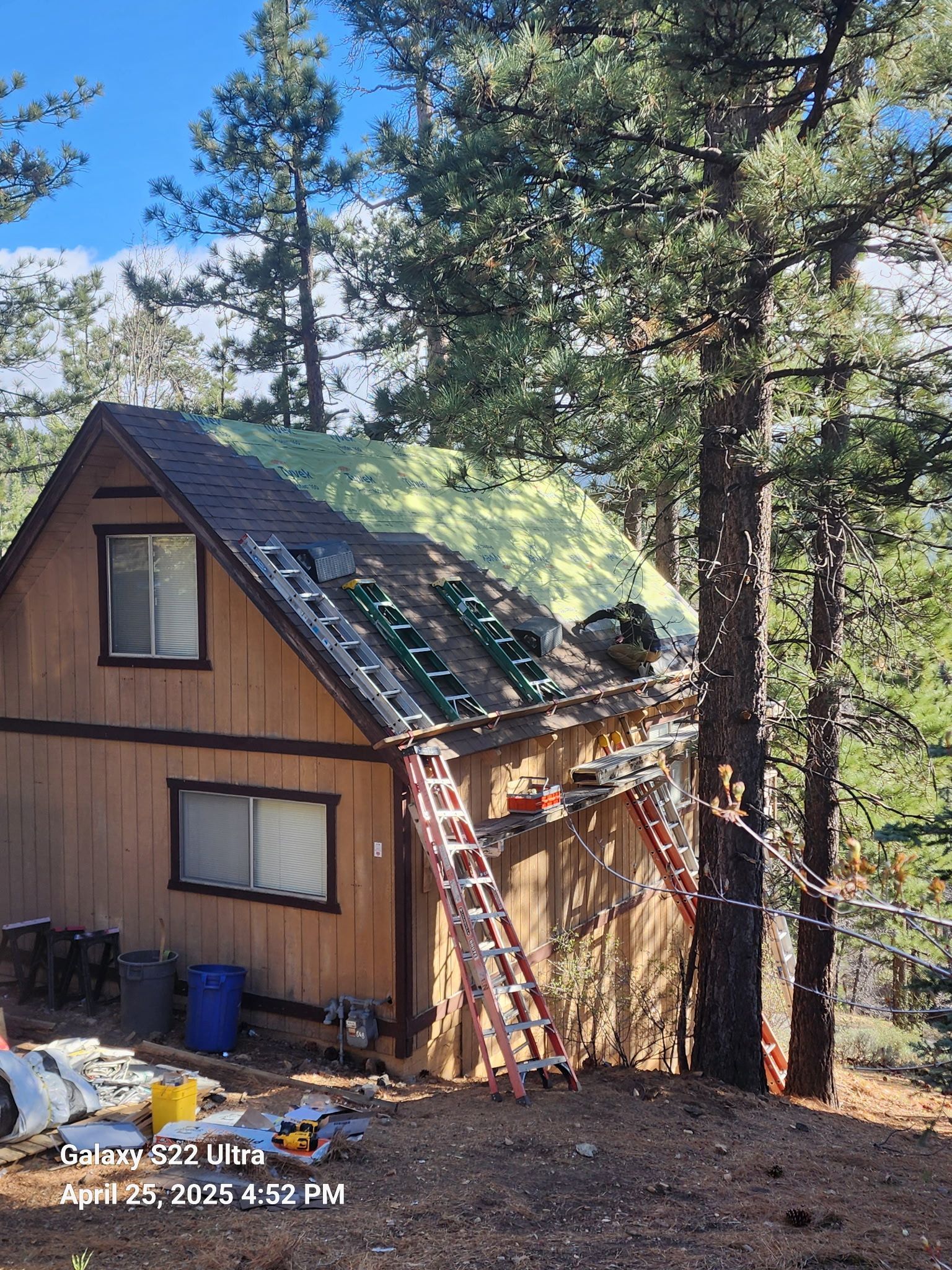 A house with a ladder on the side of it is being remodeled.