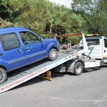 Un'auto blu viene trainata da un carro attrezzi.