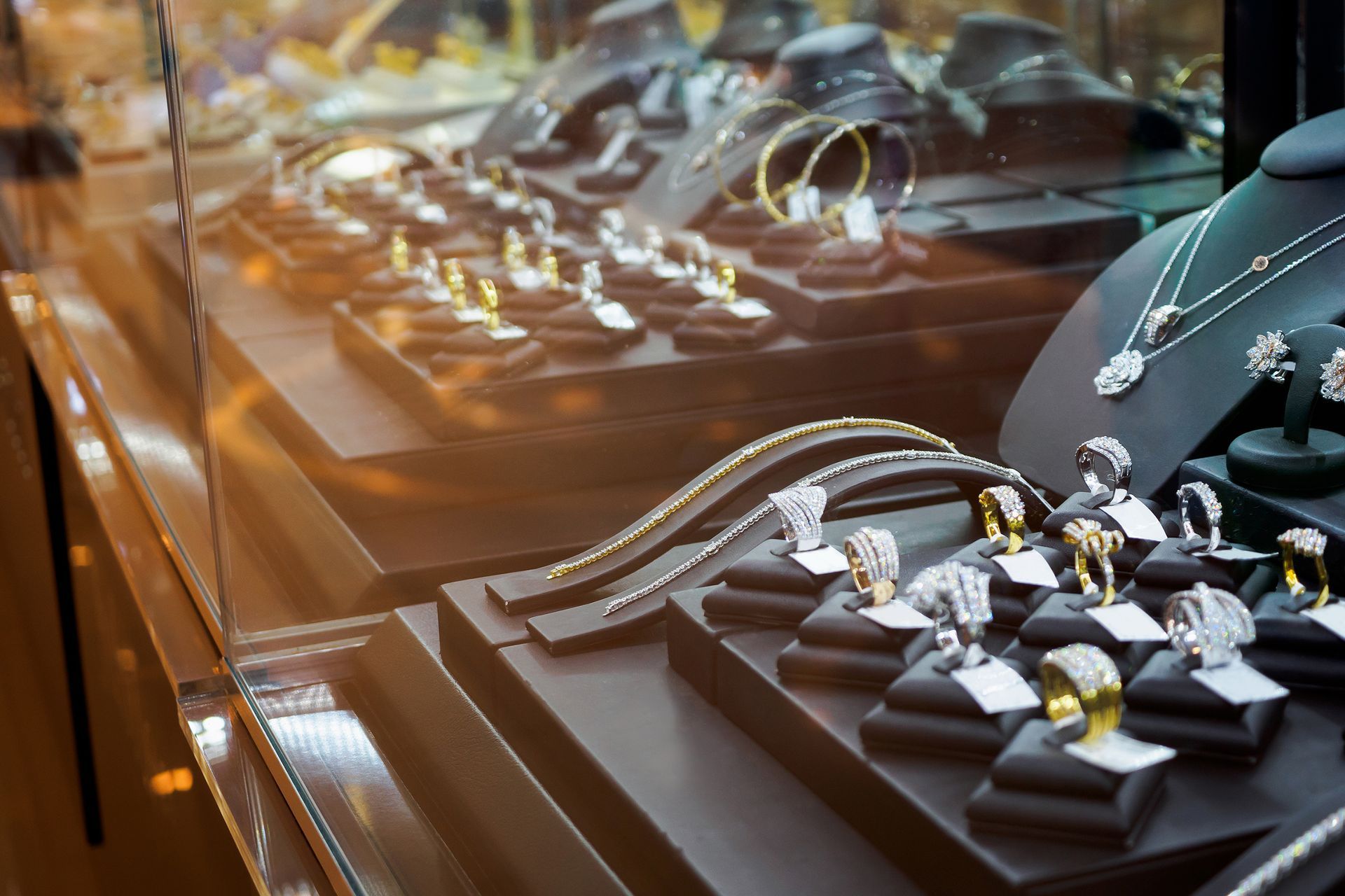 Jewelry store display with rings and necklaces arranged on black stands under warm lighting