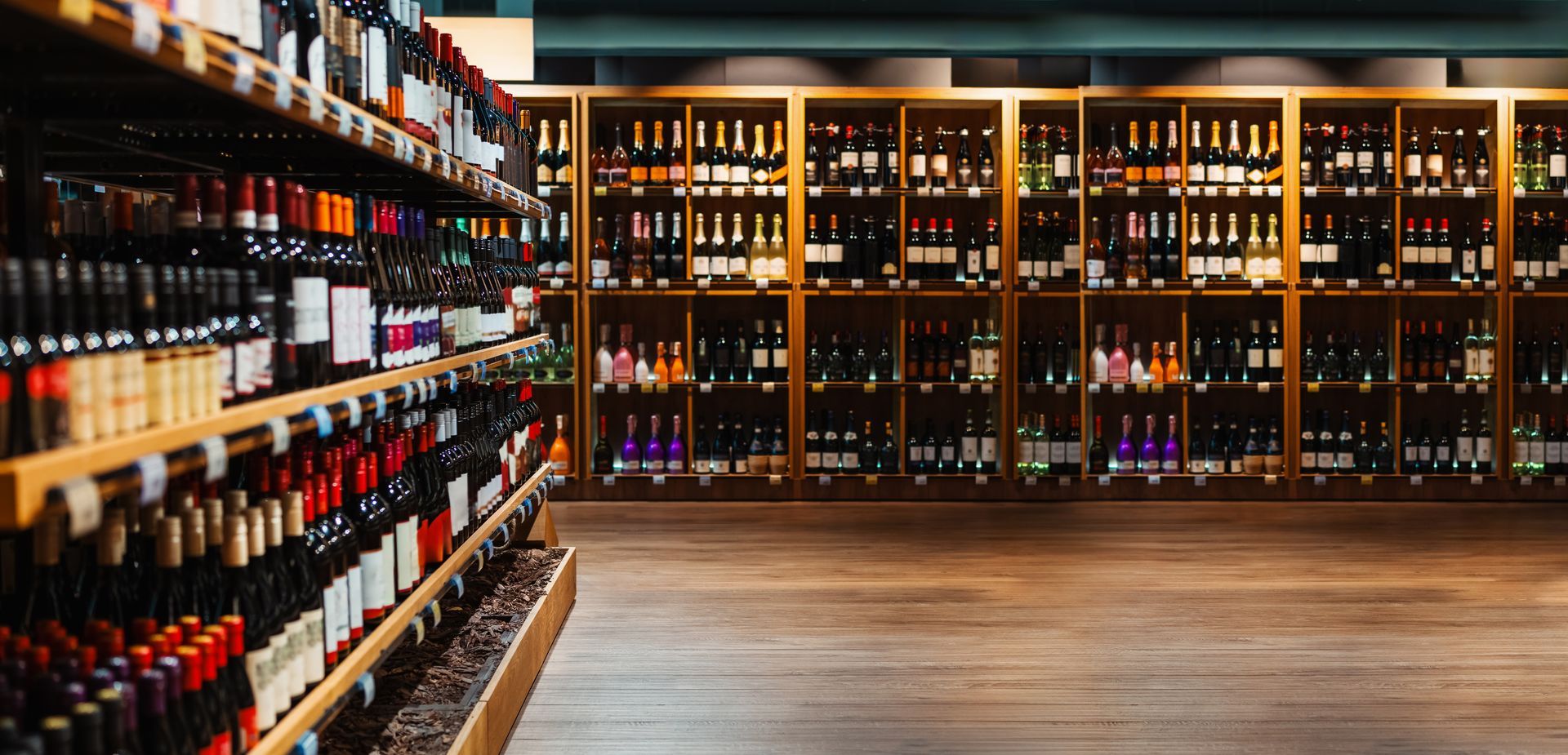 Rows of wine bottles on shelves in a well-lit store aisle with wooden display cases in the background