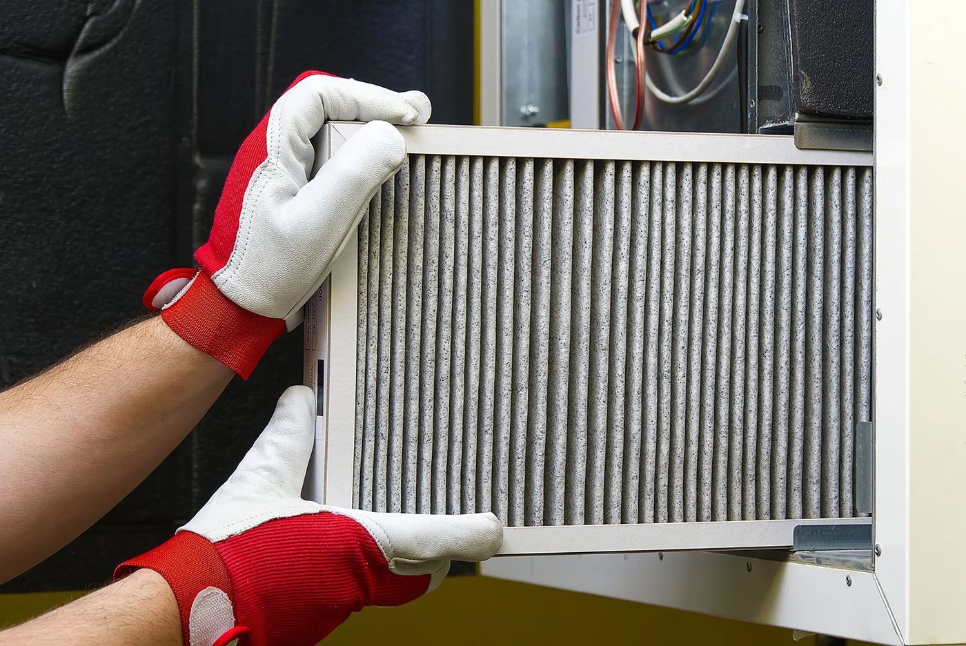 A person wearing red gloves is holding a filter in their hands.