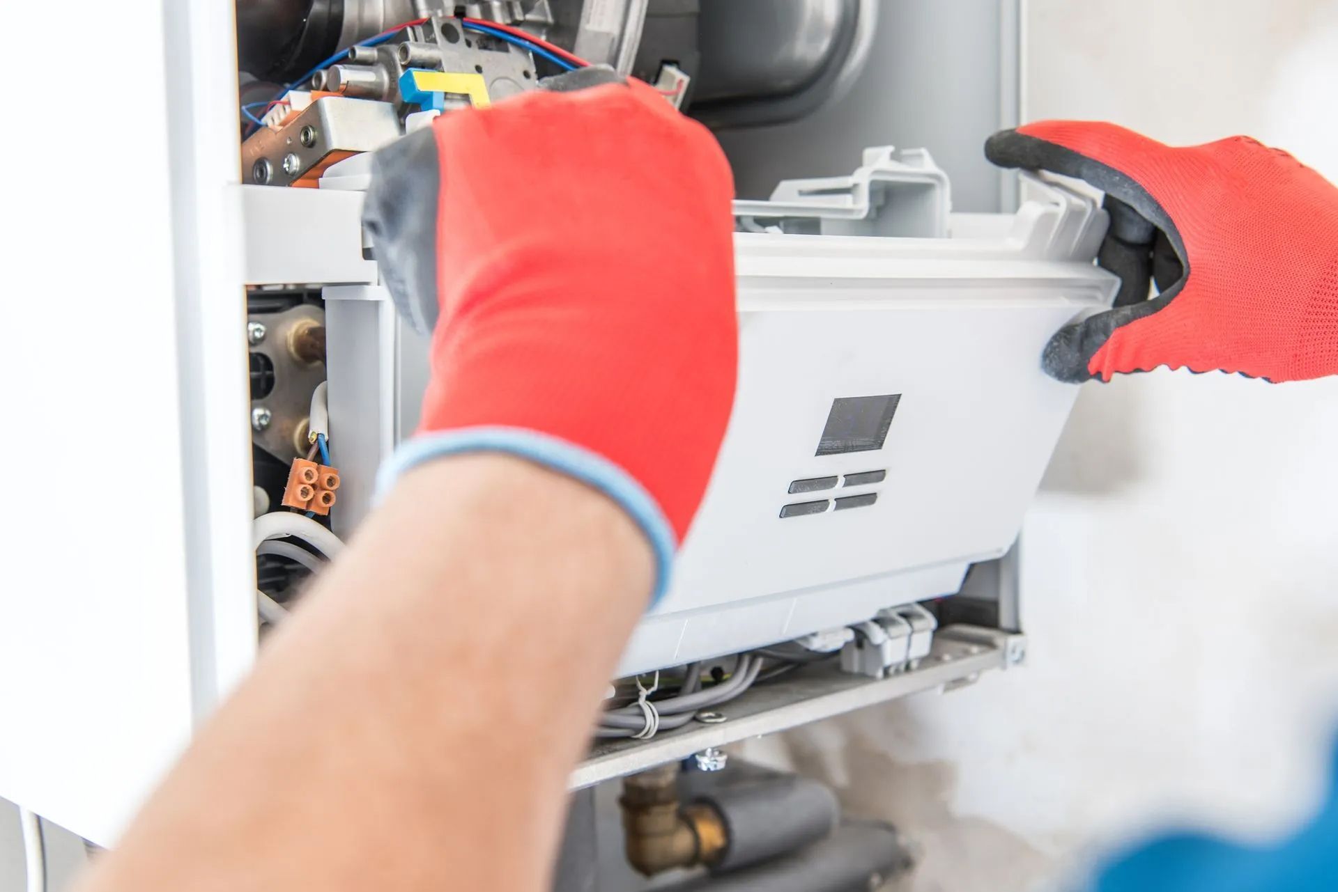 Hands in red gloves removing a white component from a furnace.