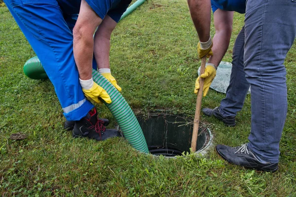 A group of men are working on a septic tank.