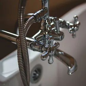a close up of a bathtub faucet with a hose attached to it .