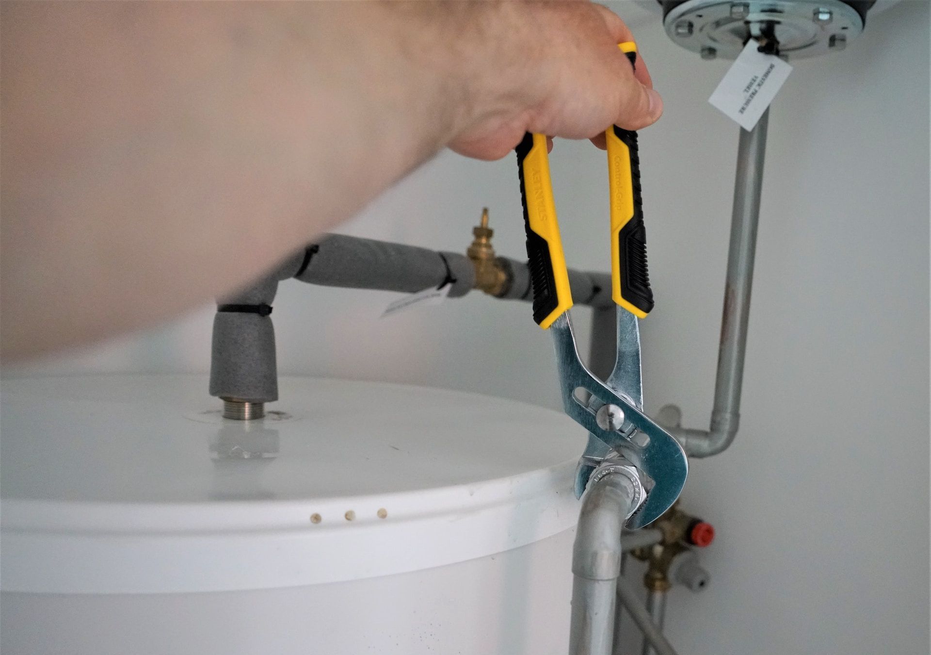 A person is fixing a water heater with a wrench.