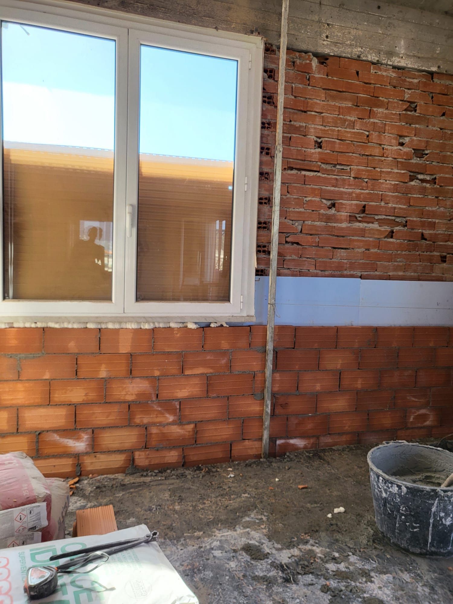Interno in mattoni con una finestra. Cantiere in costruzione, muro in mattoni grezzo e telaio della finestra visibili.
