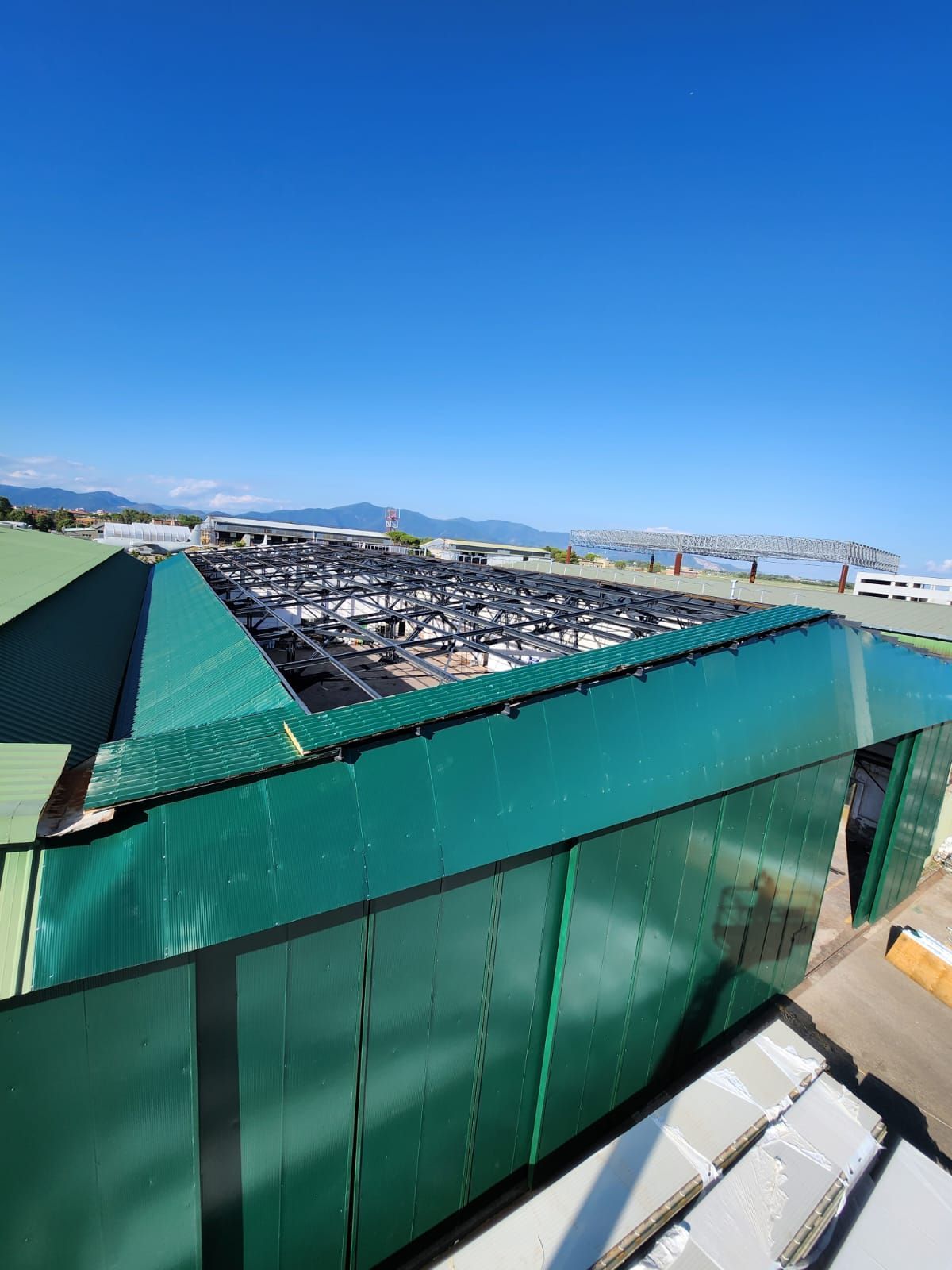 Tetto verde di un edificio industriale con un'ampia sezione aperta sotto un cielo azzurro.