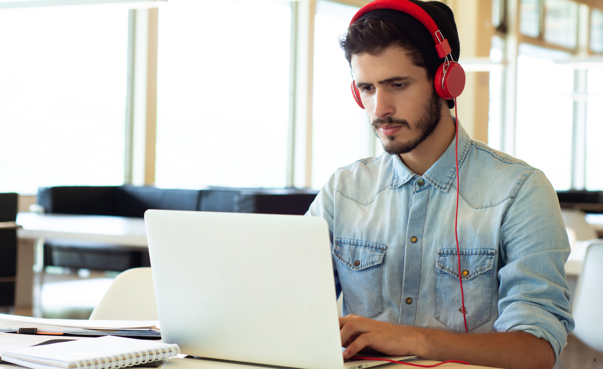 man met koptelefoon achter laptop