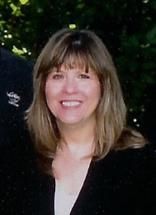 A woman in a black jacket and white shirt is smiling for the camera.