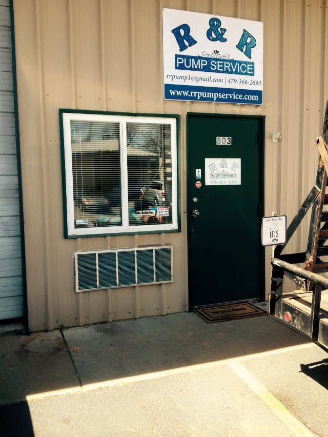 R&R Pump Service storefront with green door, window, and wall sign on a tan building