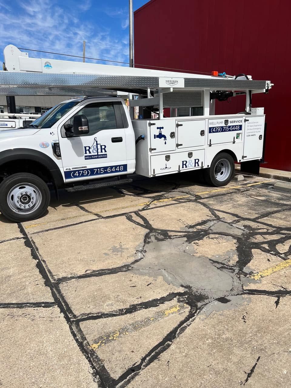 White utility truck parked outside a building under a blue sky