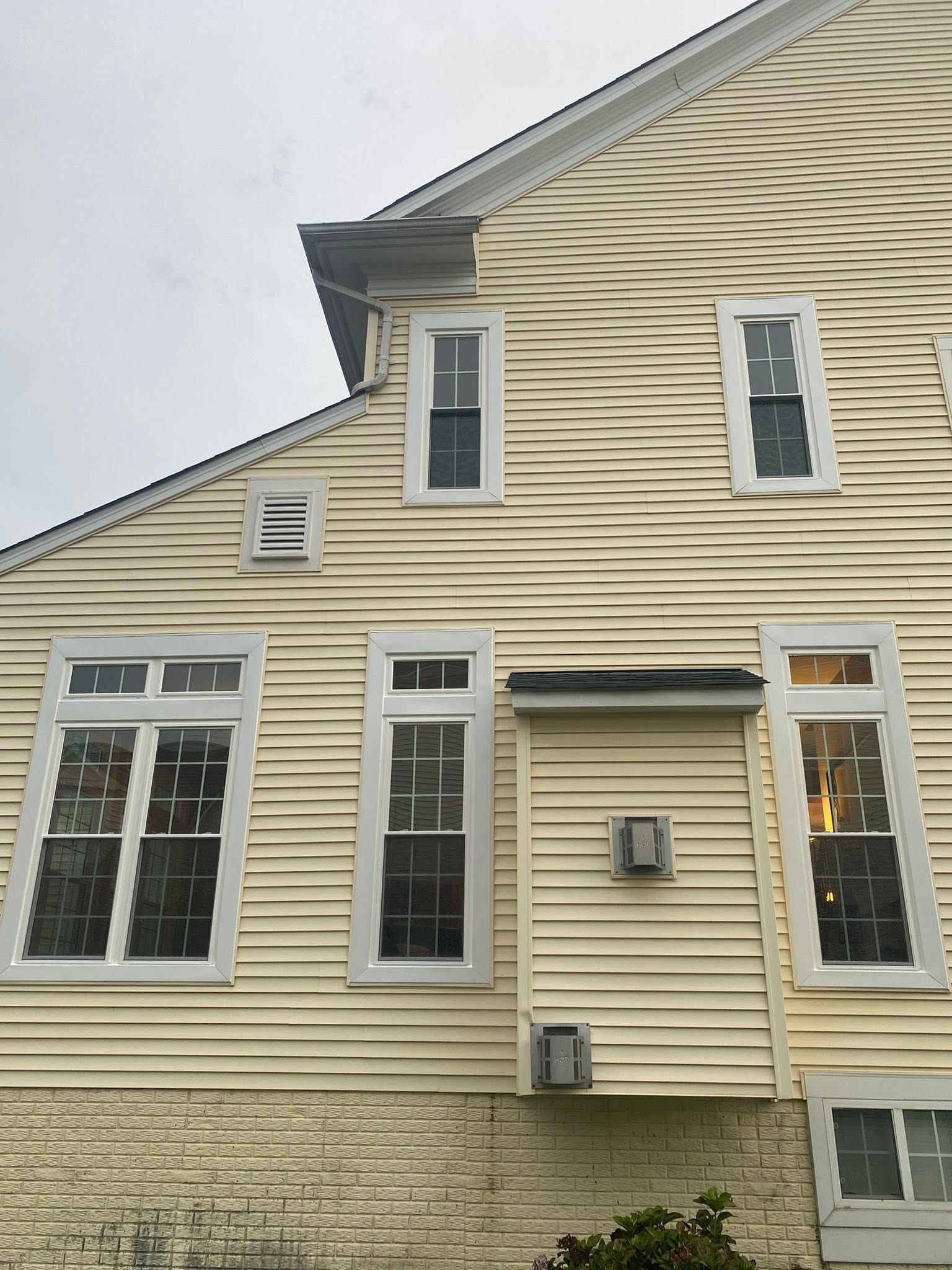Yellow clapboard house exterior with white-trimmed windows and a gray roofline