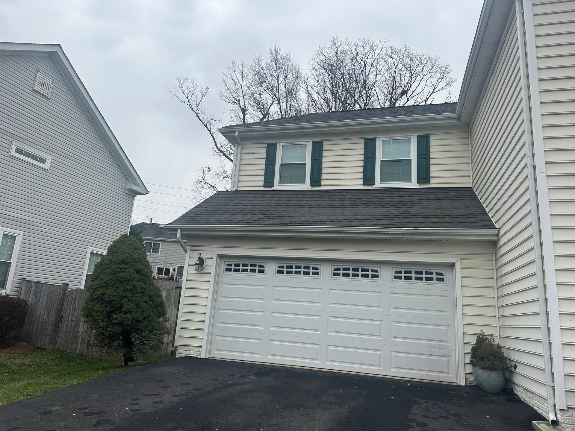 Two-story gray house with a double garage and dark roof on a cloudy day