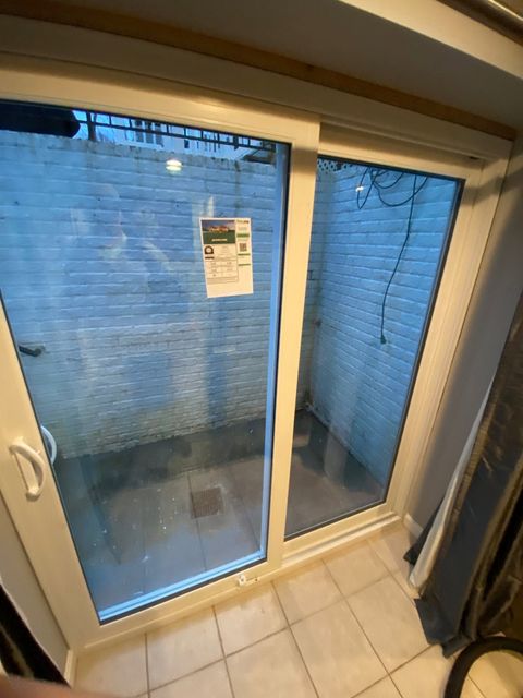 Sliding glass door with blue curtains and a notice posted on the glass, viewed from a tiled room.