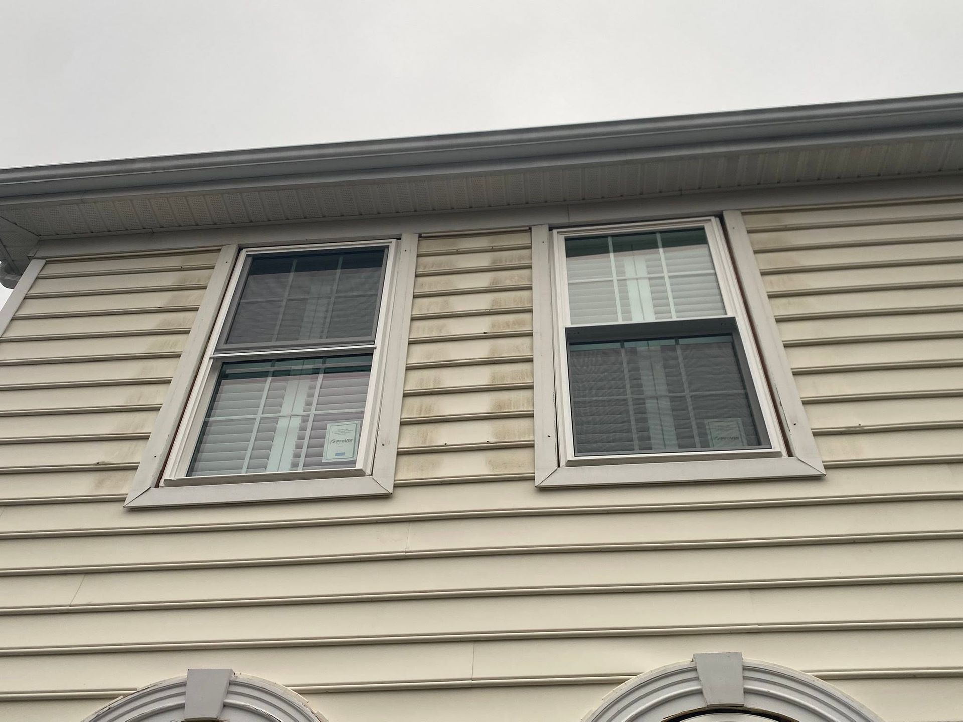 Exterior of a beige house with two upper-story windows and white shutters