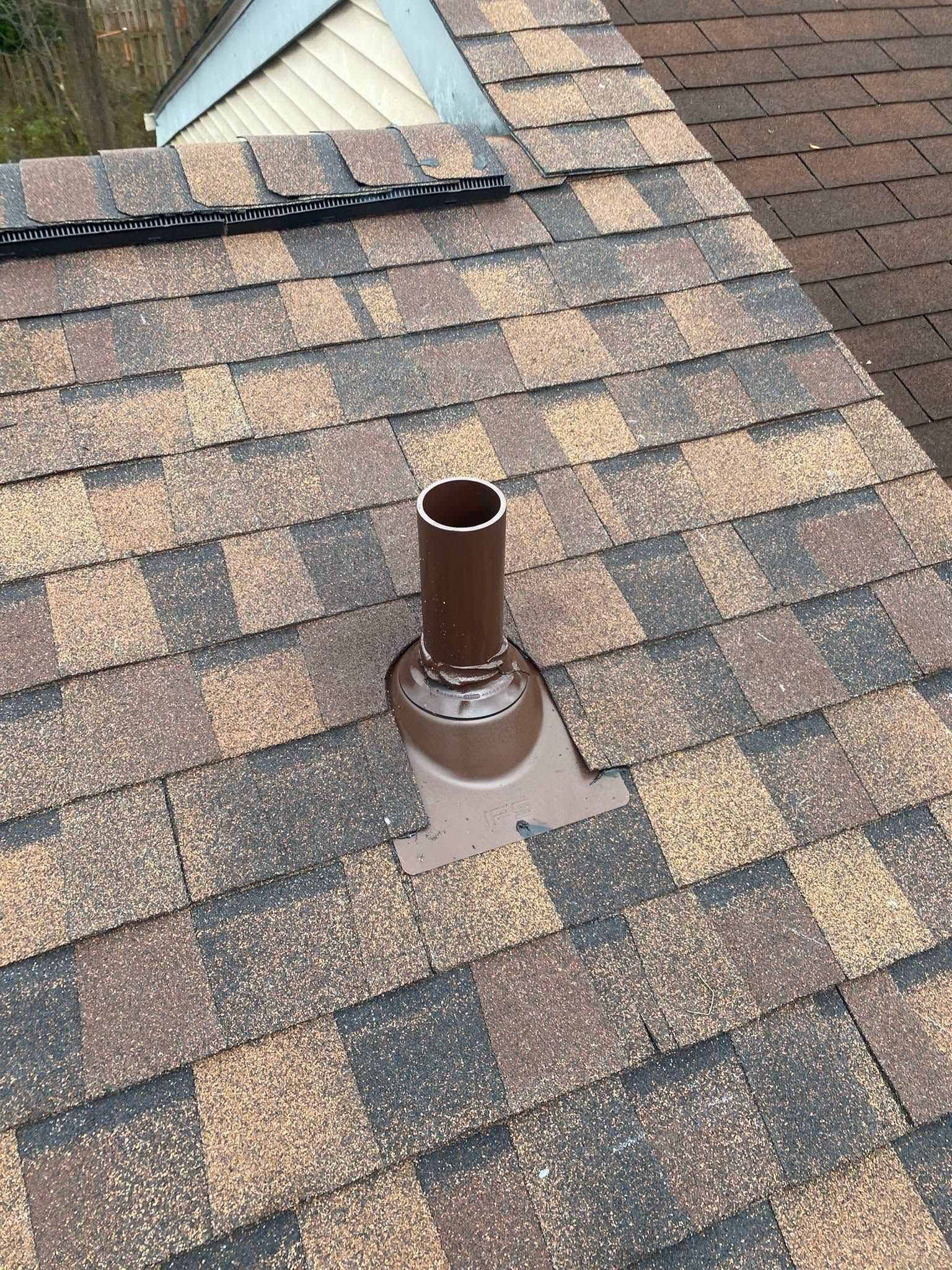Roof shingle vent pipe flashing on a brown asphalt shingle roof