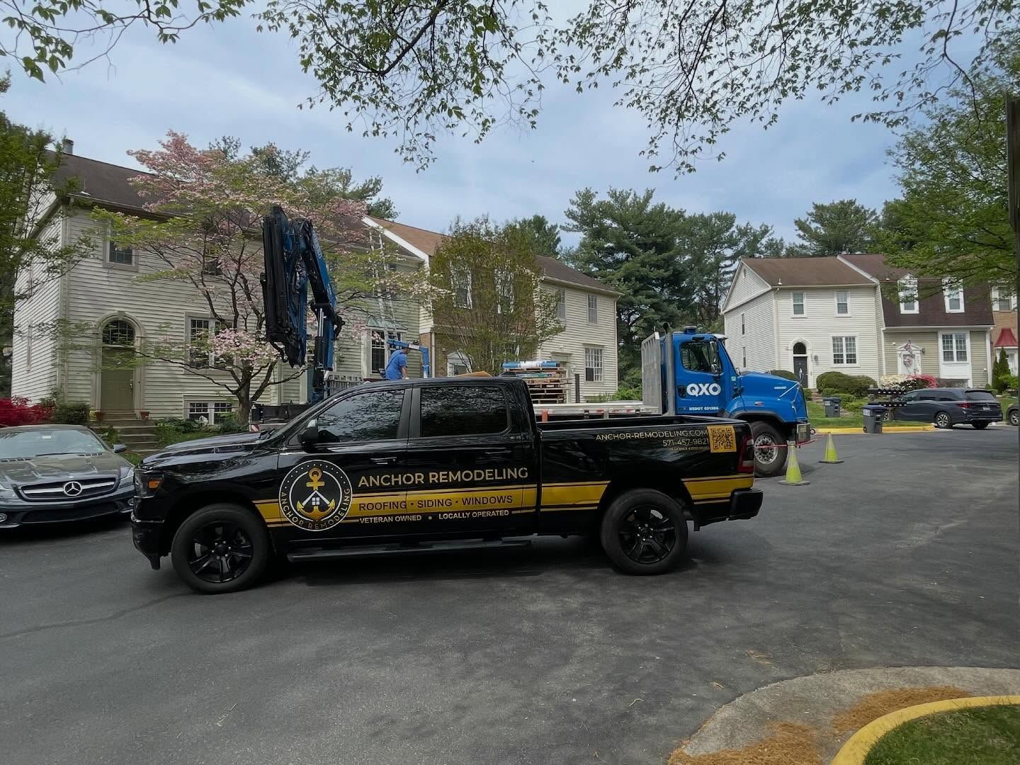 Tow truck loading a black car in a residential parking lot with apartment buildings nearby