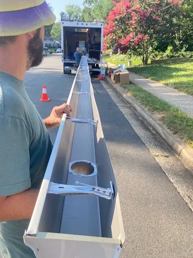 Worker aligning a long metal beam from a truck on a residential street