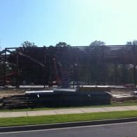 Partially built steel frame structure beside a road under a bright sky