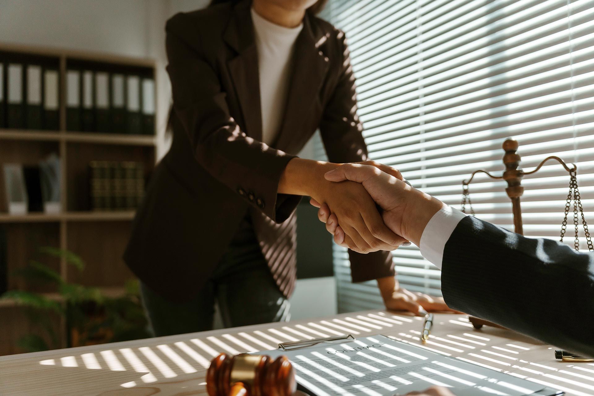 A family lawyer shakes hands with a client in their office after reaching an agreement in a lawsuit. A family lawyer shakes hands with a client in their office after reaching an agreement in a lawsuit.