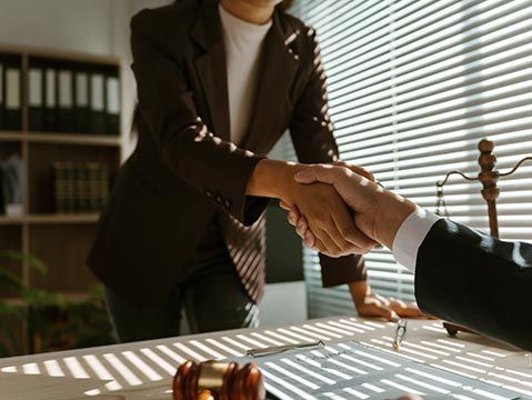 A family lawyer shakes hands with a client in their office after reaching an agreement in a lawsuit. A family lawyer shakes hands with a client in their office after reaching an agreement in a lawsuit.