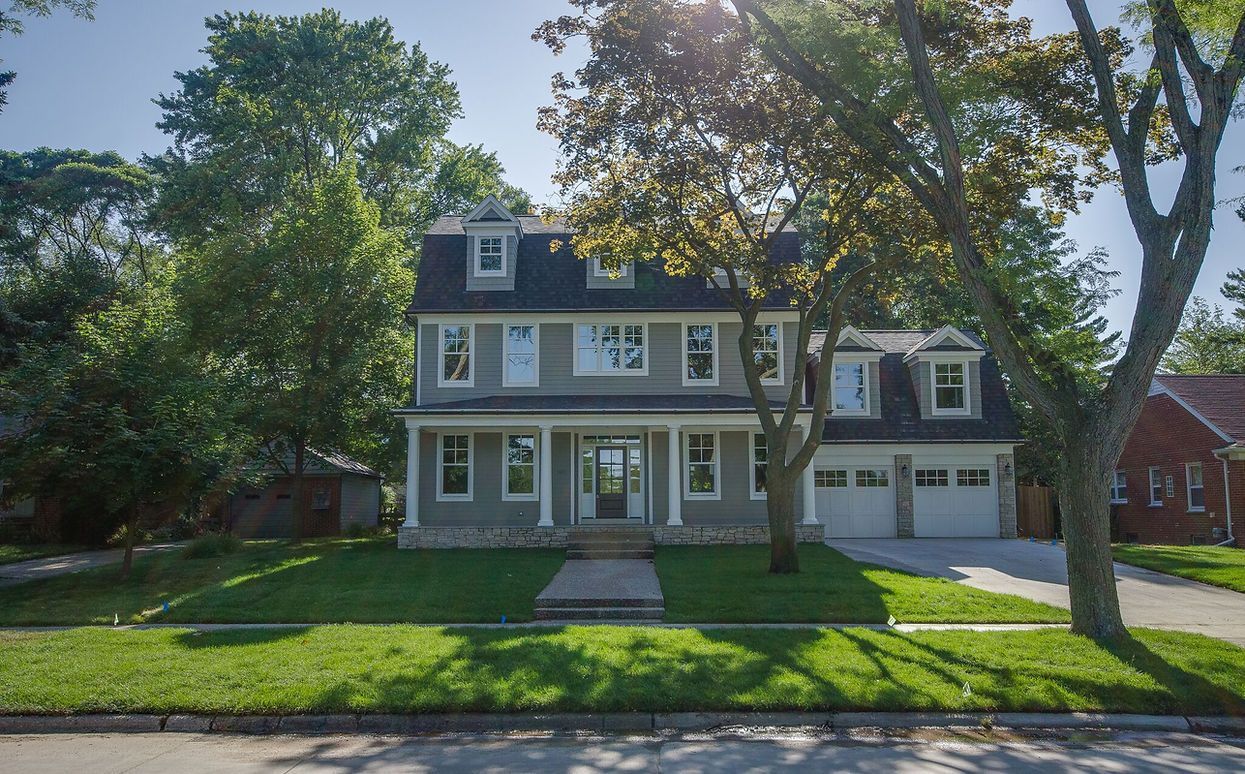 A large house with a black roof is surrounded by trees