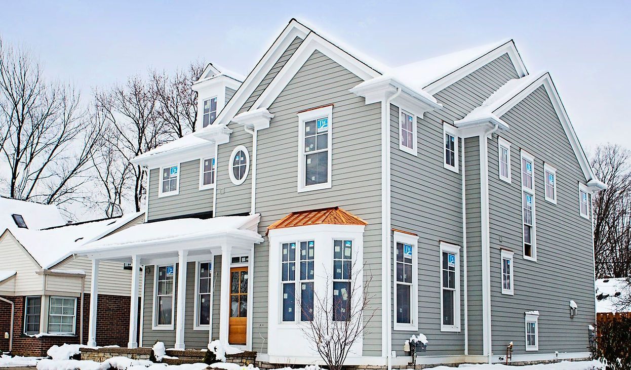 A large house with a lot of windows is covered in snow.