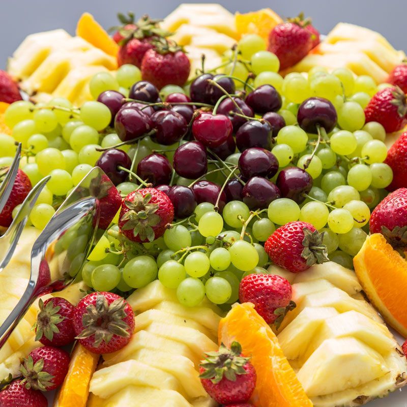 Fruit platter with green and purple grapes, strawberries, apple slices, and orange wedges