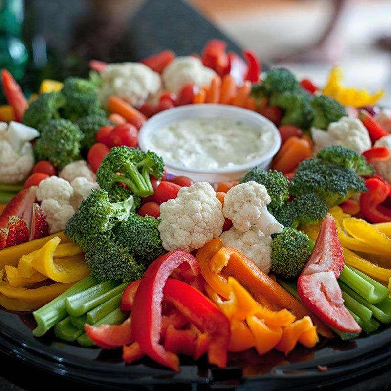 Fresh vegetable platter with broccoli, cauliflower, peppers, tomatoes, and dip in the center