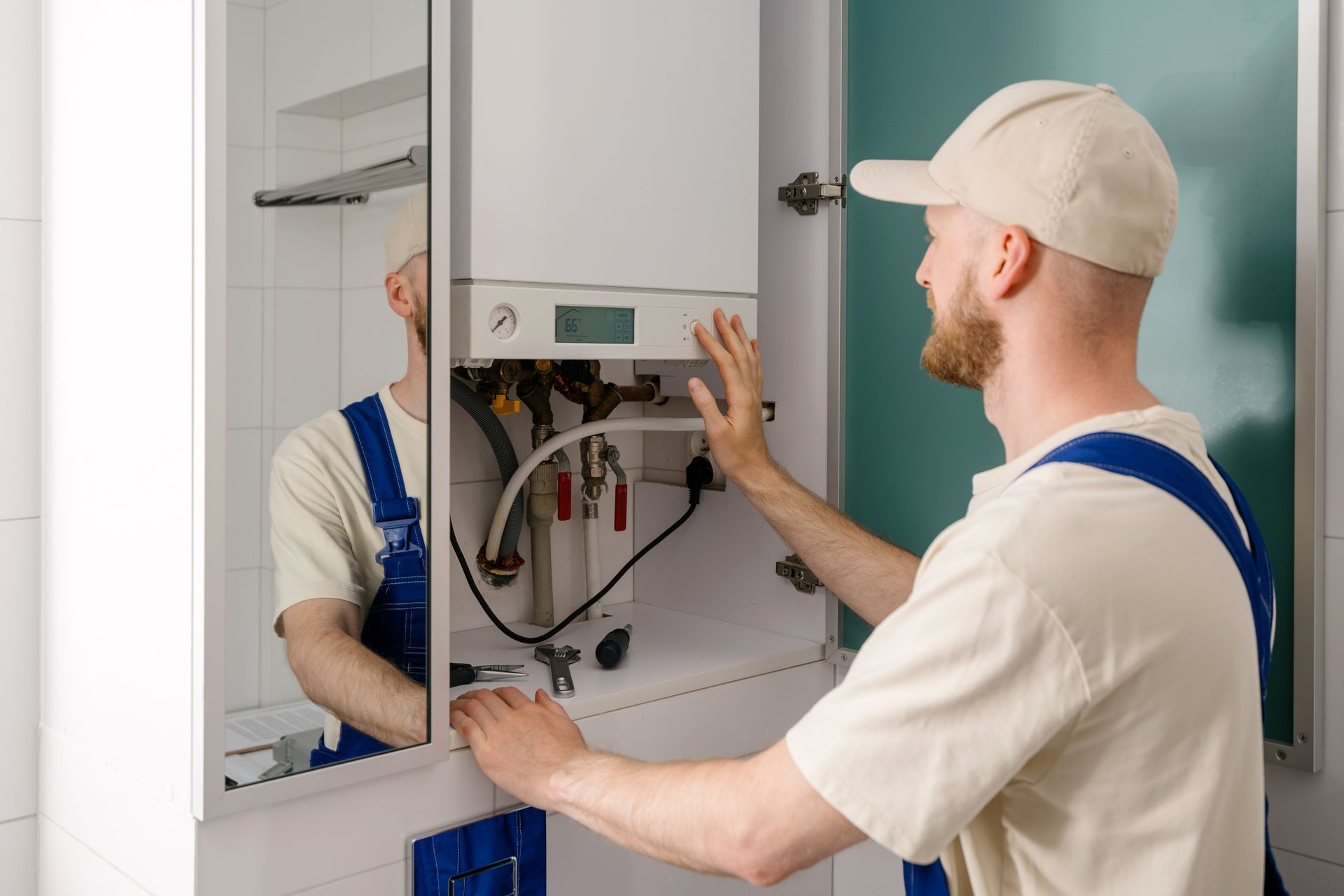 Repairman maintaining gas boiler in modern bathroom for efficient heating. Repairman maintaining gas boiler in modern bathroom for efficient heating.